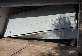 Garage door in Darien, IL visibly off tracks and leaning against the driveway, showing need for repair