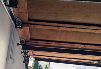 Close-up of a worn garage door roller and rusted curved track prior to replacement in Darien home