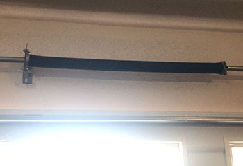 Close-up view of a newly replaced black torsion garage door spring installed above a residential garage door in Westmont, IL